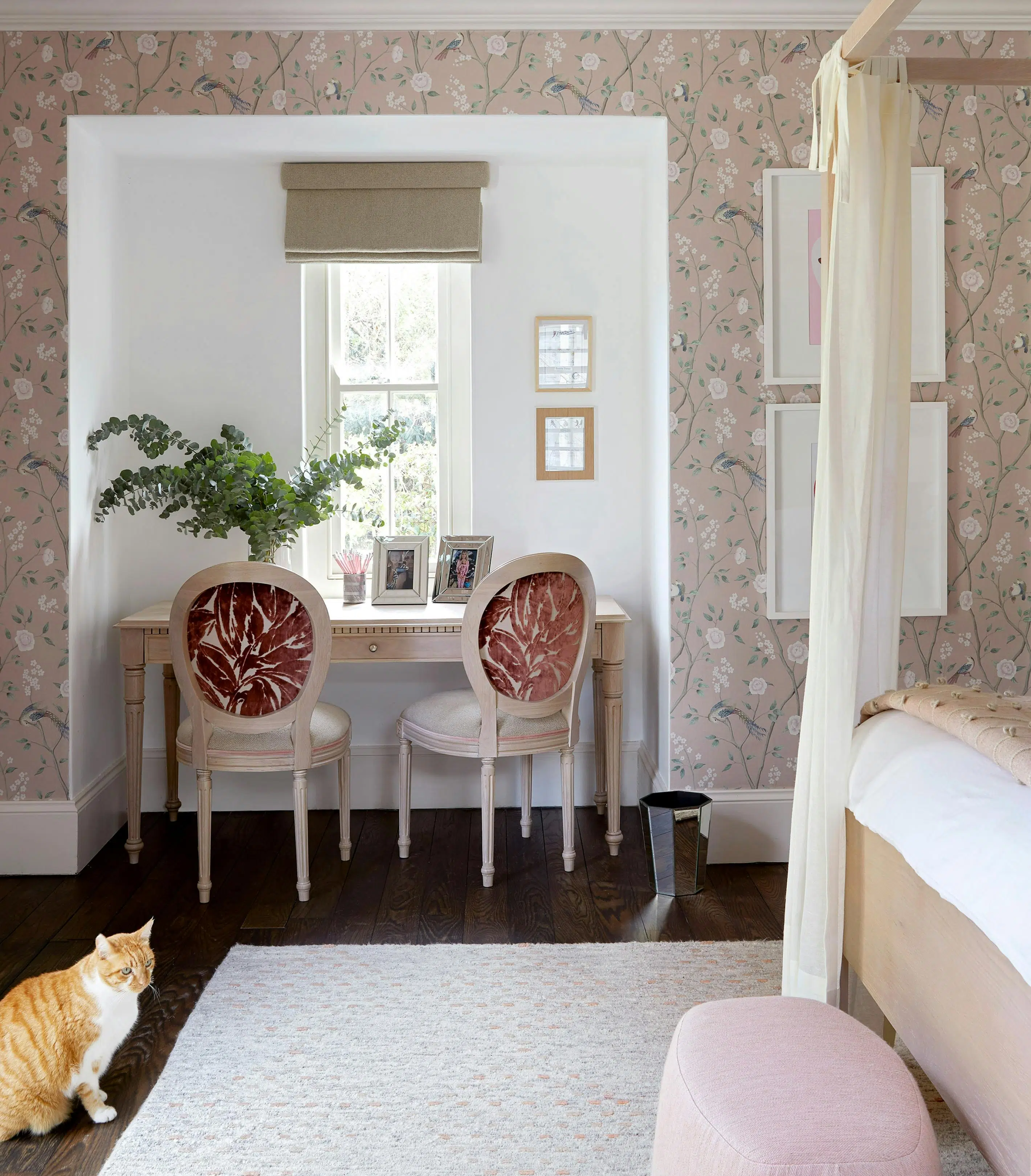 A bedroom with two chairs and desk in the centre of the image with the bed on the right.