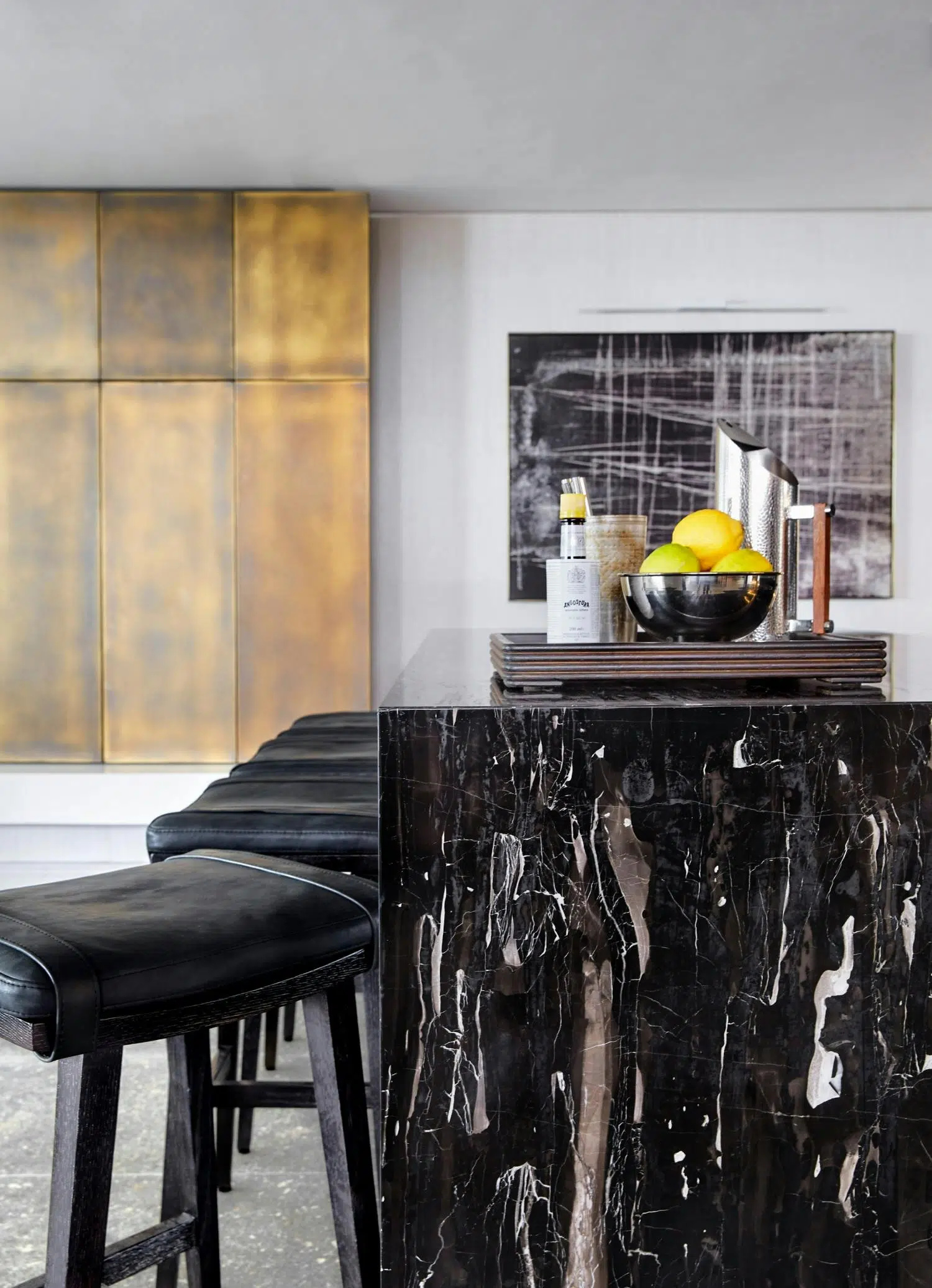 A waterfall, black marble bar with bar stools to the left and artwork with a similar pattern to the marble in the background.