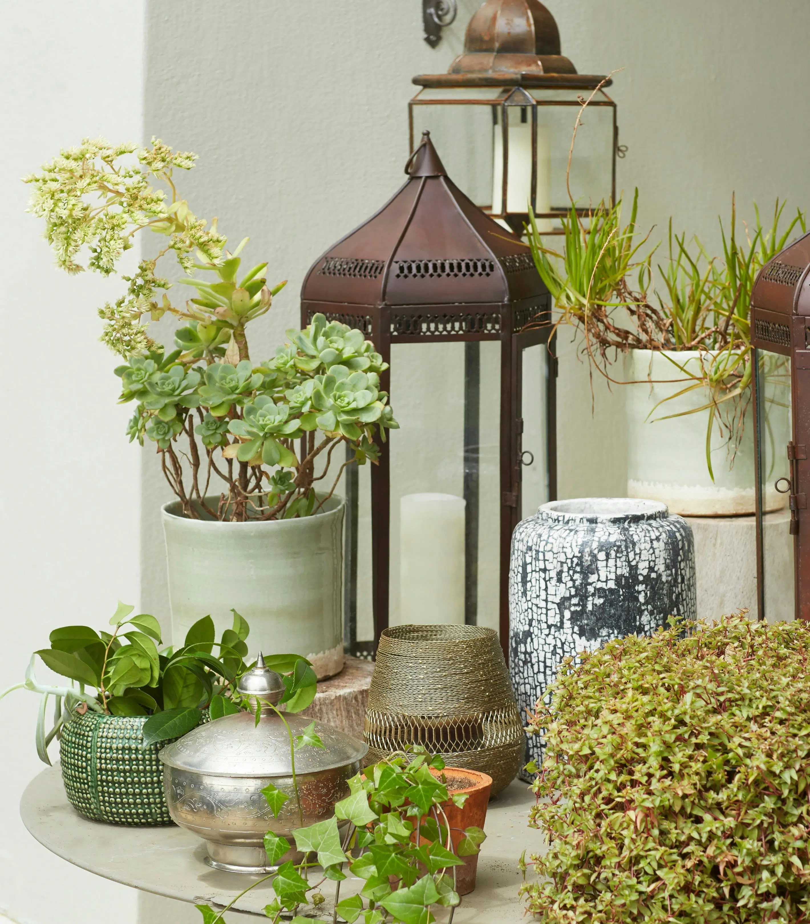 Decorative accents including planters, votives and vases on a table.