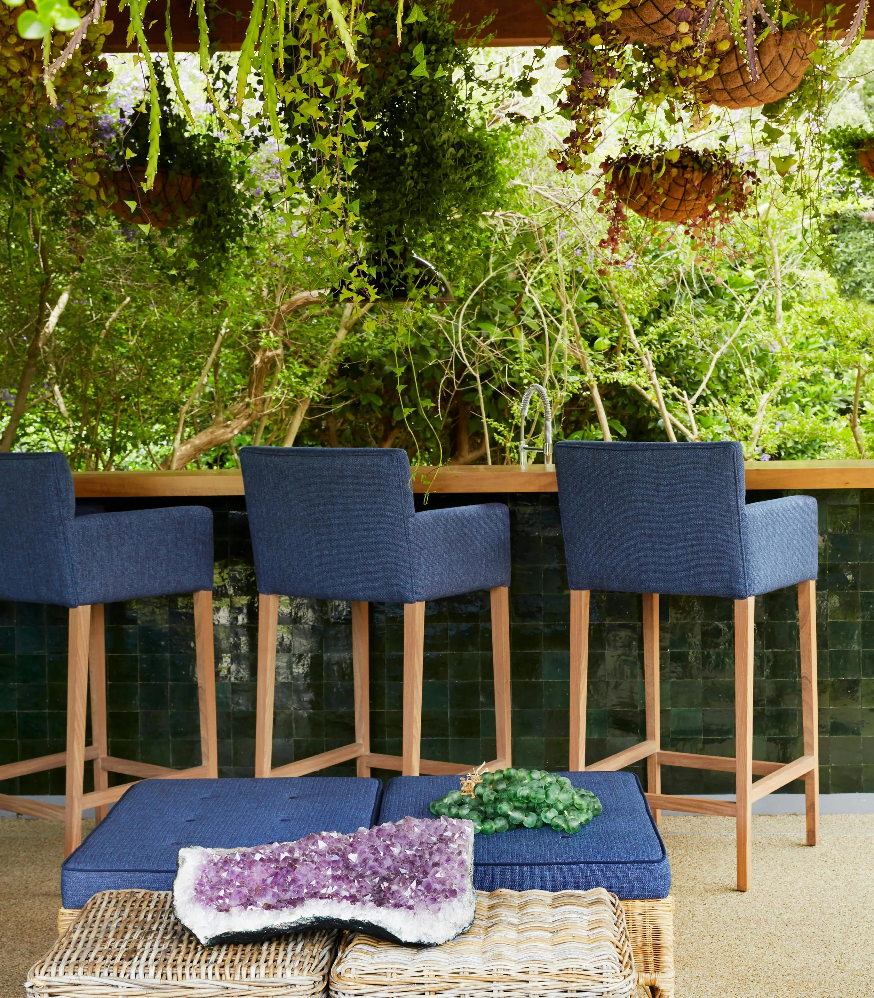 Three bar stools at an outdoor, wooden bar.