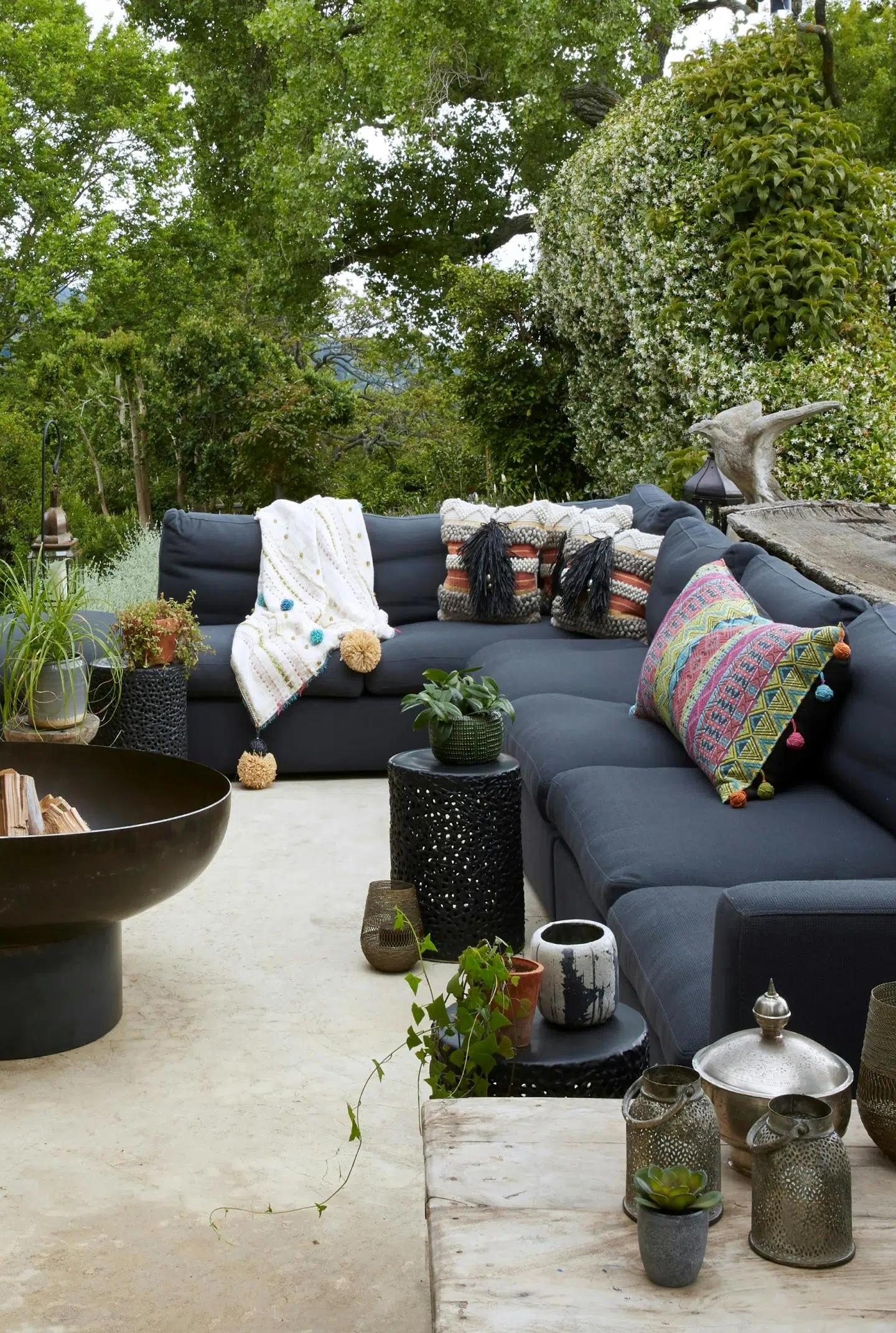 Close-up of an outdoor, Moroccan-inspired fire pit next do a charcoal outdoor sofa.