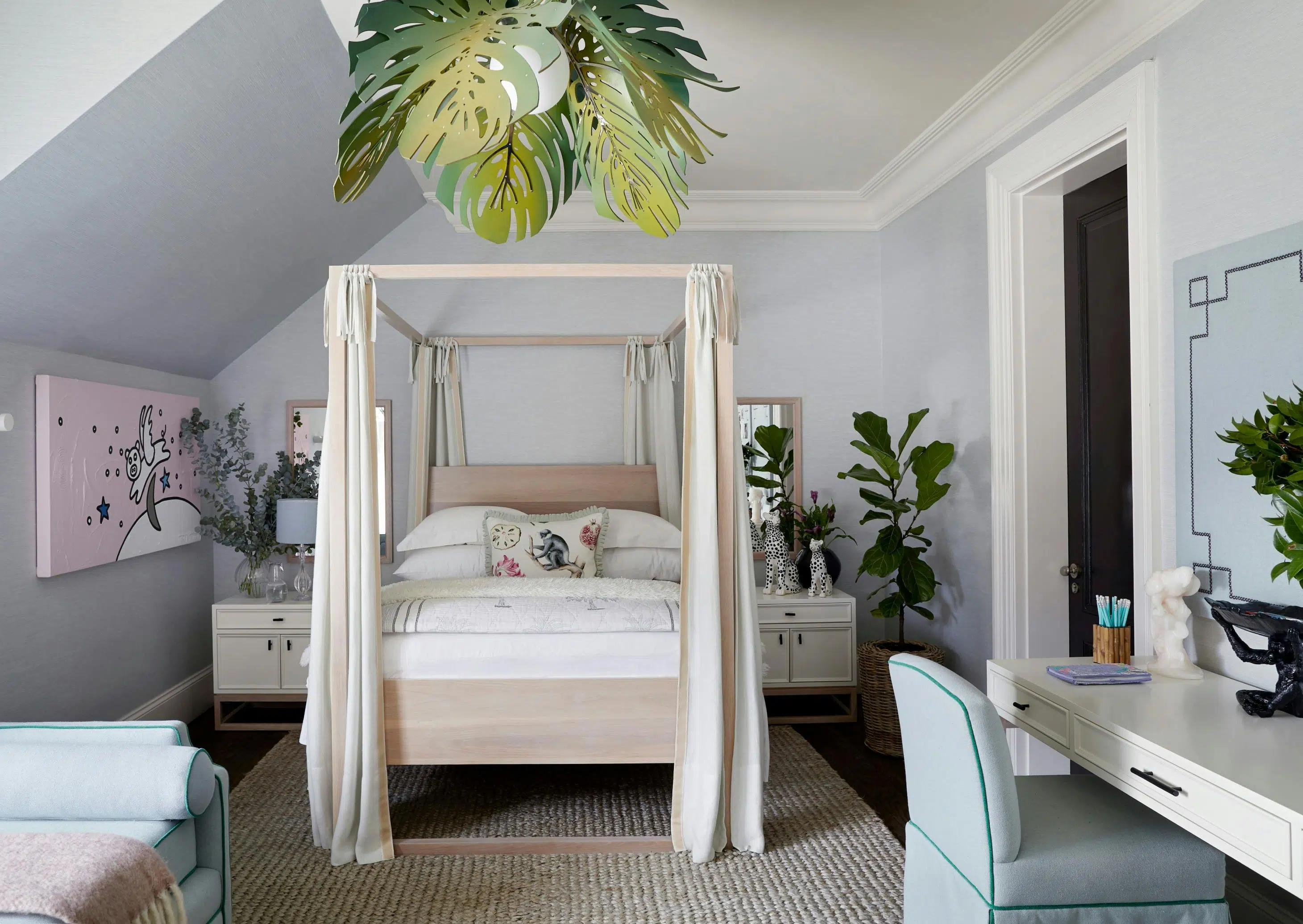 A modern children's bedroom with a 4-poster wooden bed, a desk to the right and pink artwork to the left.