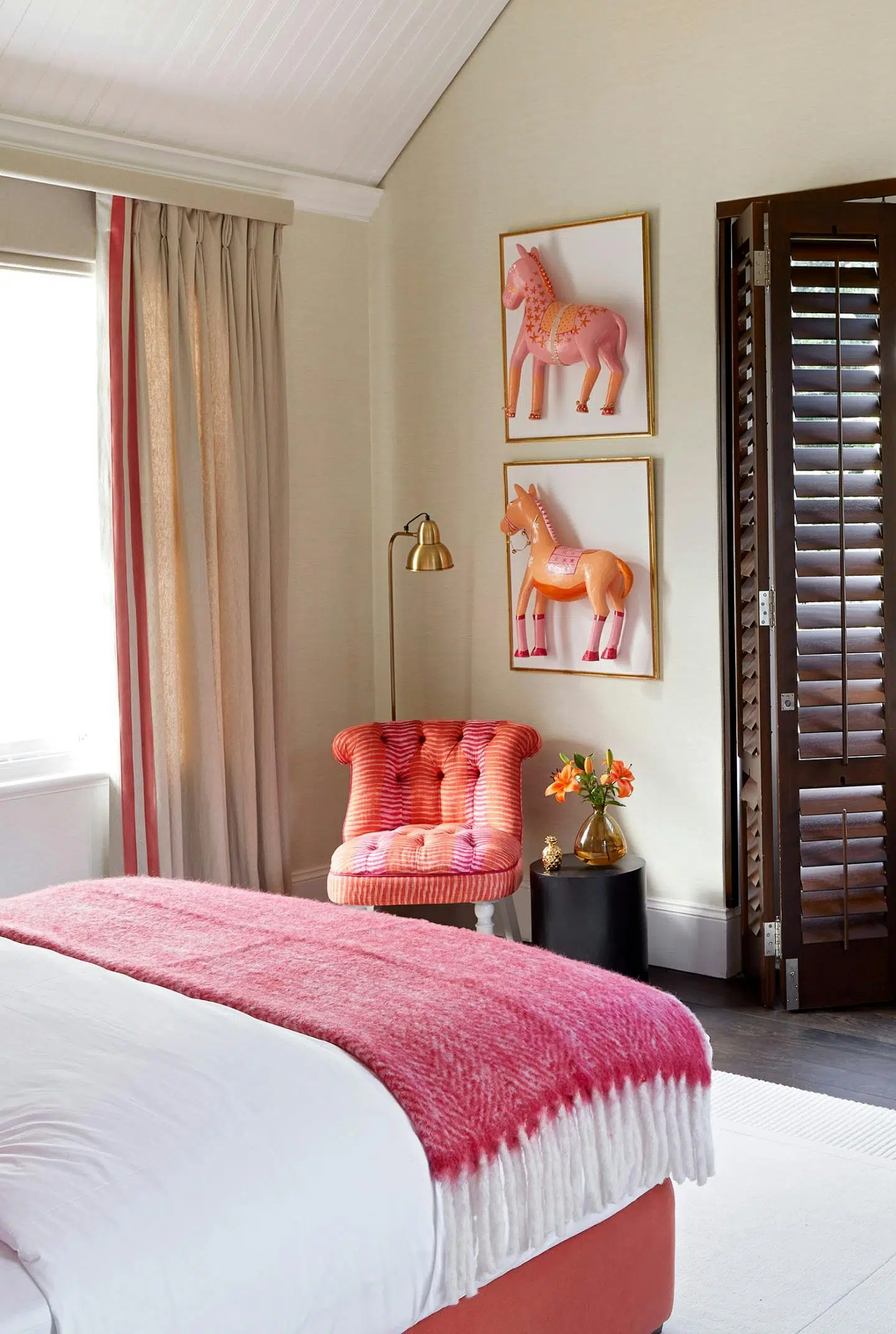 Close-up of a child's bedroom with pink and white bedding and frames on the wall with 3D horses, also in pink.
