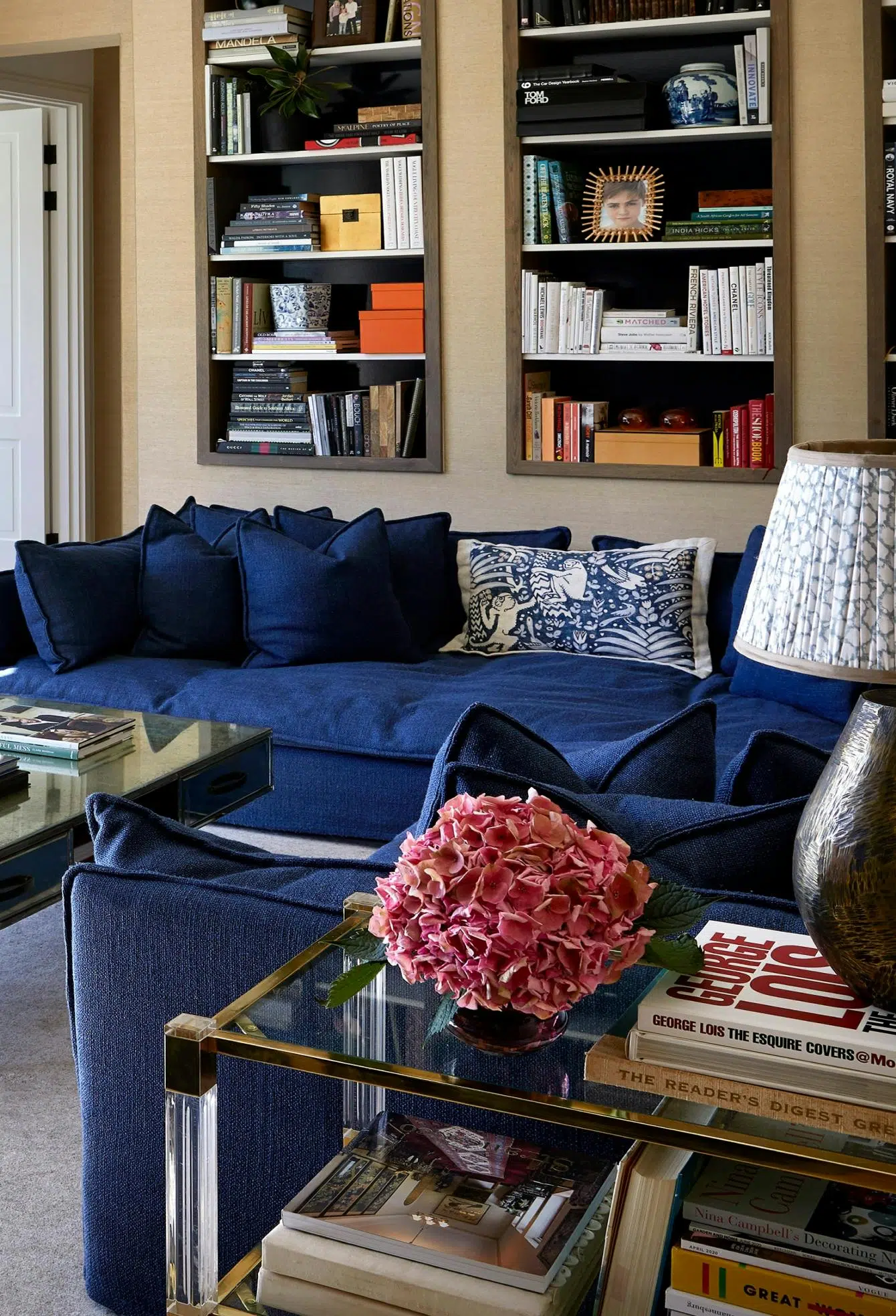 Close-up of a room that features a deep blue sofa, book and other decorative accents on the wall in the background.