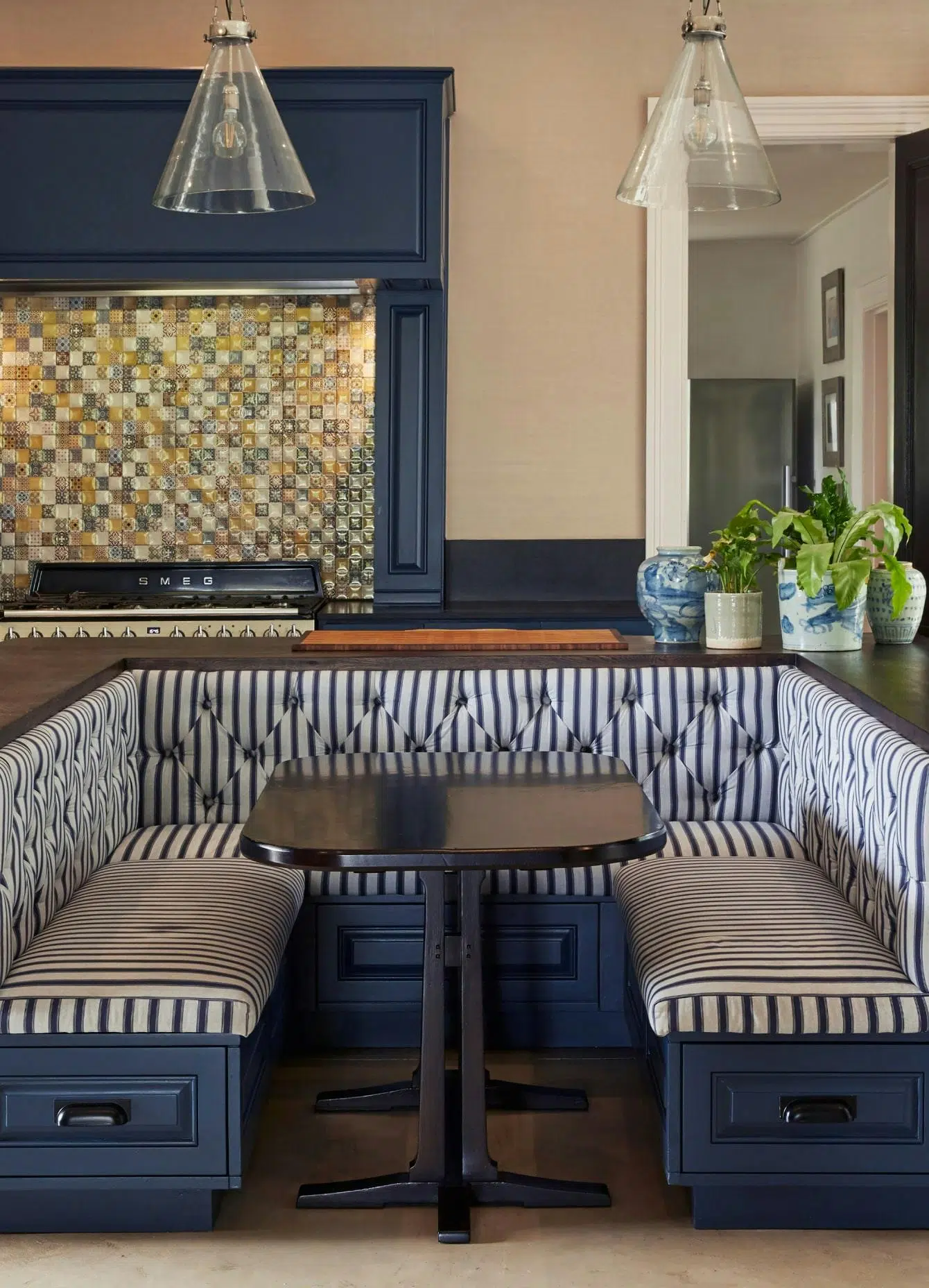 A kitchen banquette in a dark blue colour with a wooden top and black and white striped upholstery.
