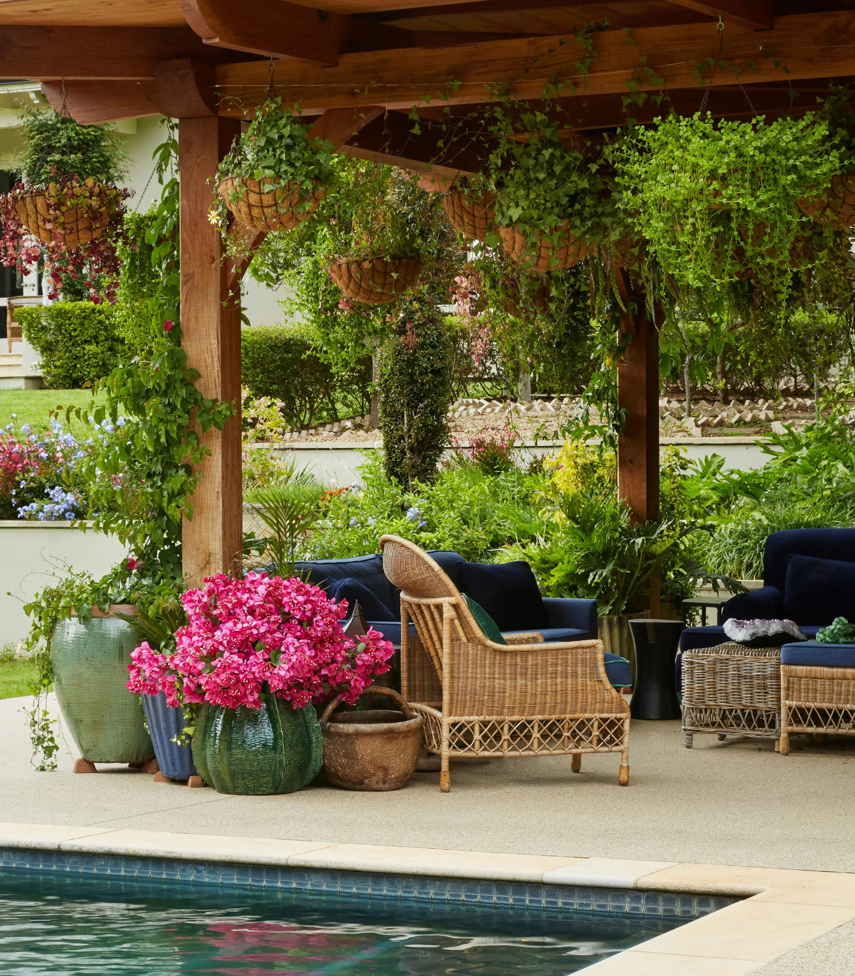An outdoor entertainment area with rattan furniture with flowers in  planters in the foreground.