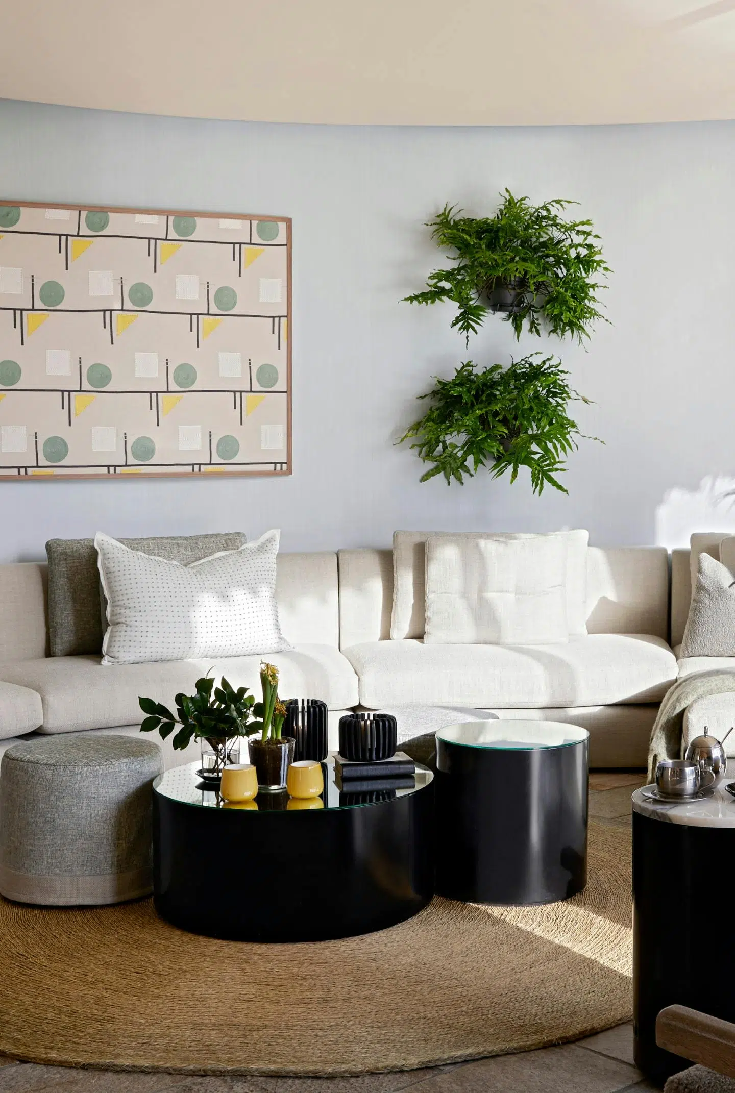 A contemporary living room with circular side and coffee tables on a round mat with a curved sofa against the back wall.