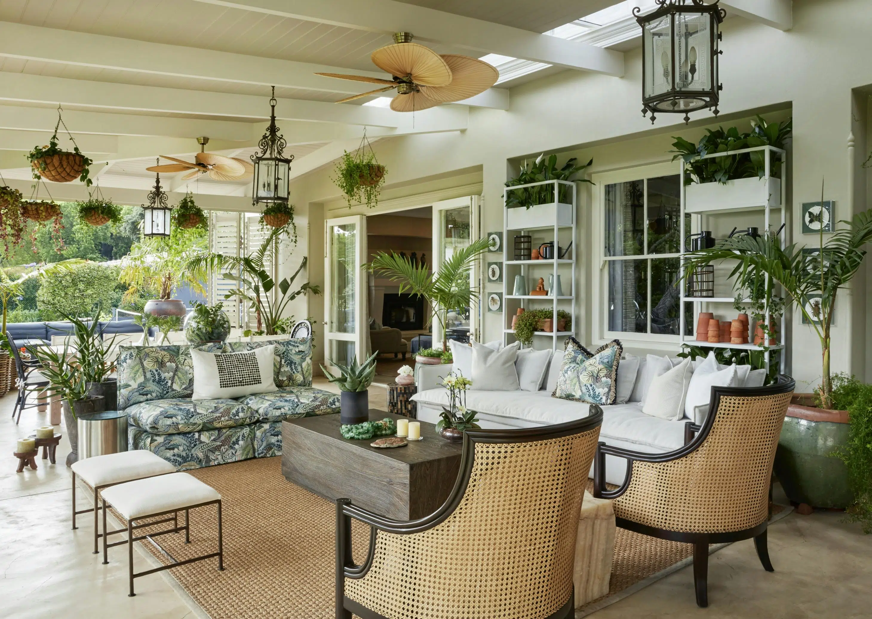 An outdoor entertainment area with a wooden coffee table in the middle, surrounded by two sofas and two rattan armchairs.