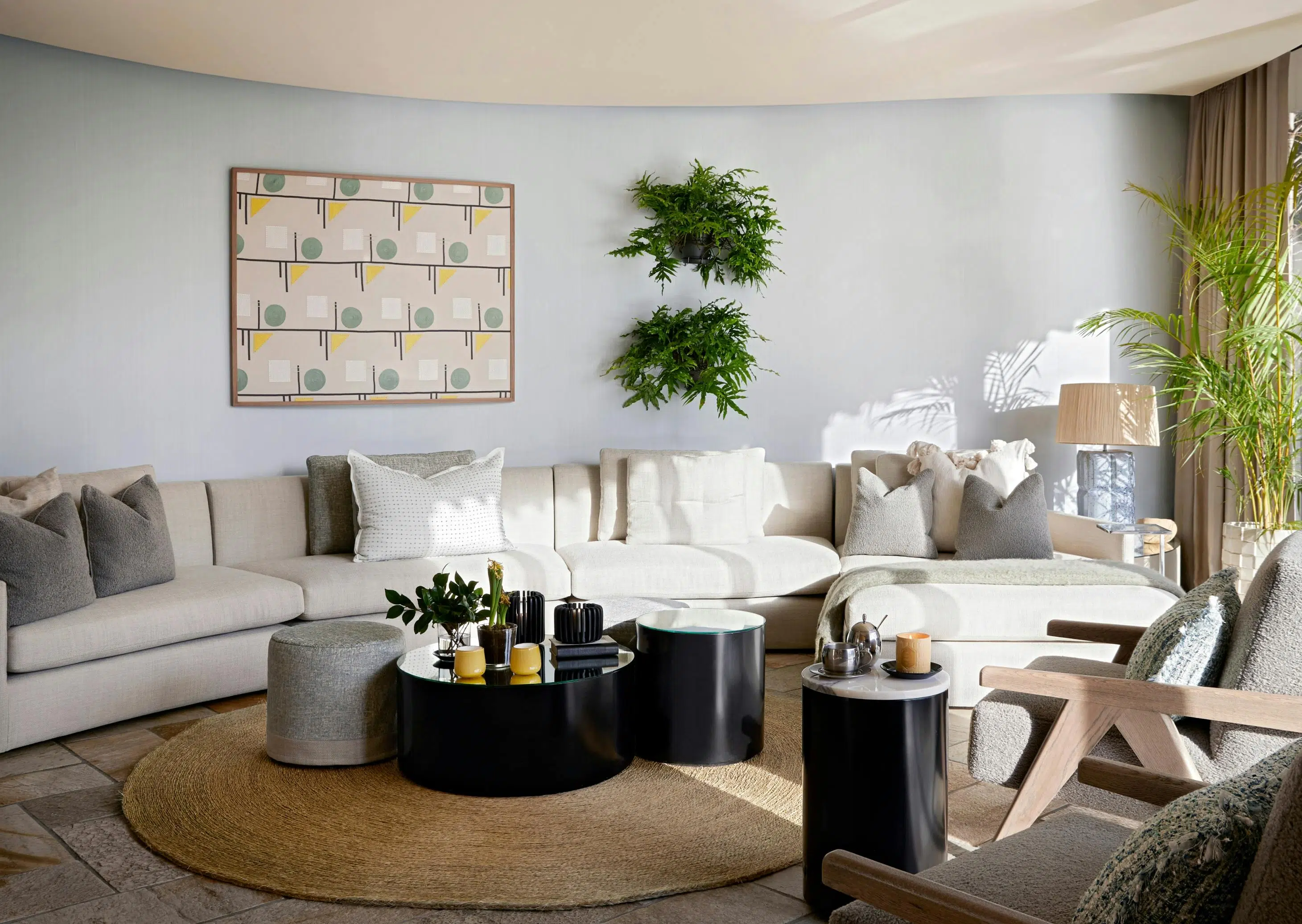 A contemporary living room with circular side and coffee tables on a round mat with a curved sofa against the back wall.