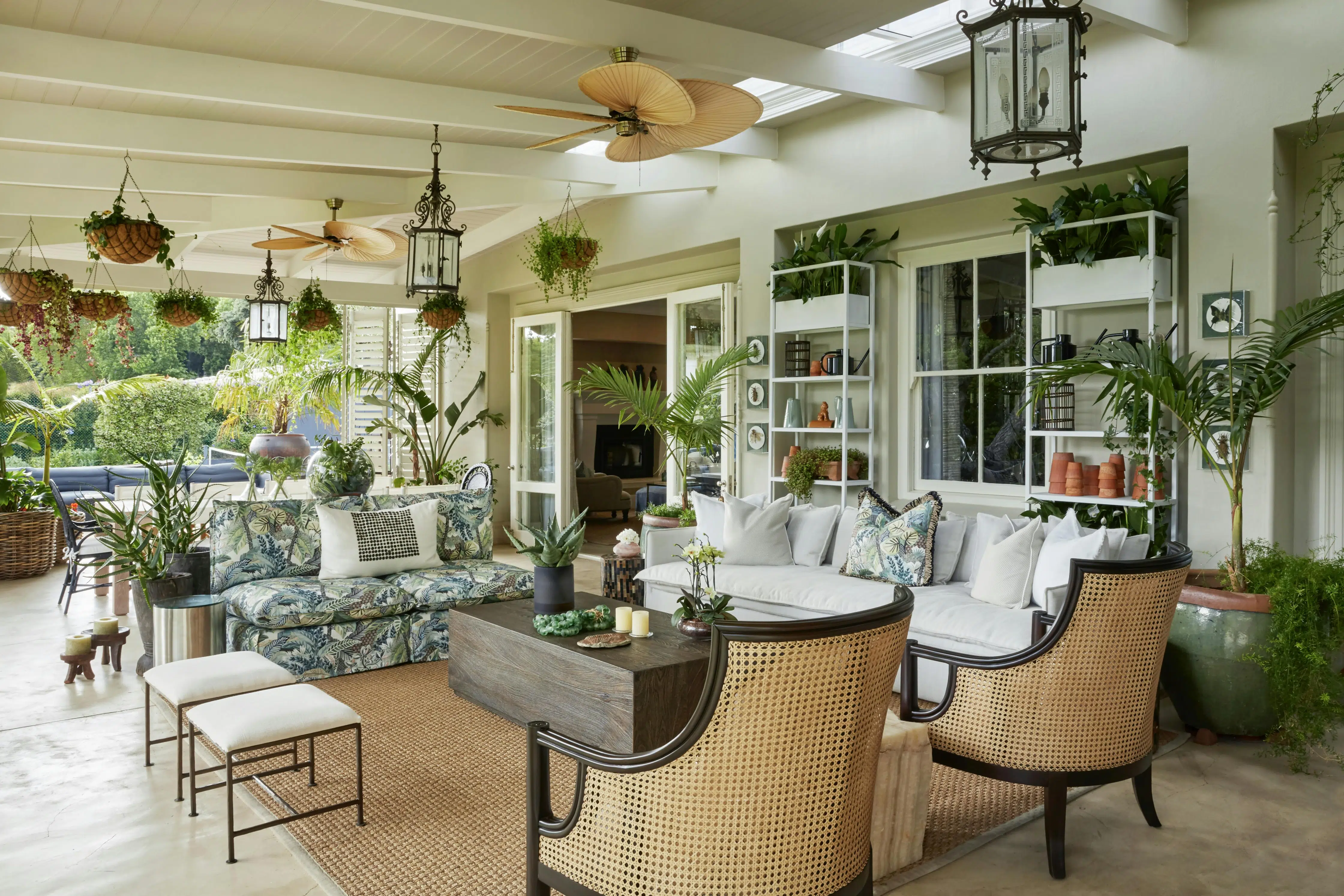 An outdoor entertainment area with a wooden coffee table in the middle, surrounded by two sofas and two rattan armchairs.